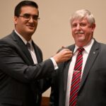 Dules Area Association leadership members offering a ceremonial pin to a member jacket