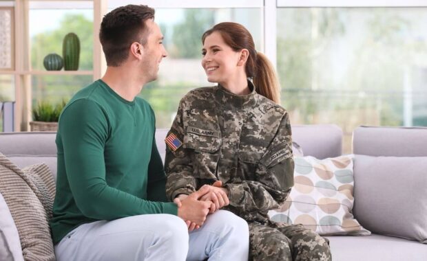 woman in military uniform with her husband on sofa at home