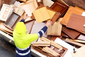 bricklayer worker in motion blur in construction site depositing rubble in container for pickup by truck