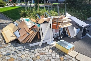 heap of assorted discarded household items and furniture piled up on a cobblestone street